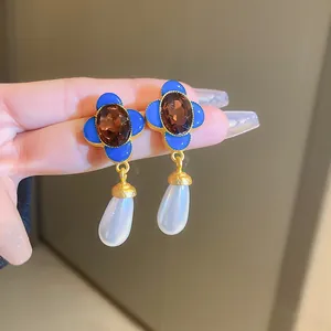 Close-up of French vintage blue flower earrings with brown gemstone and pearl drop.