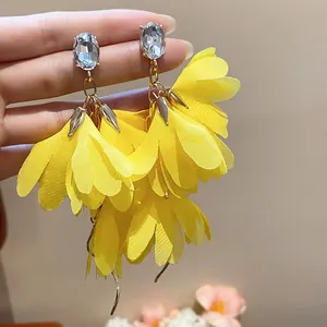 Dettaglio degli orecchini a fiore in chiffon giallo con borchie di strass ovali lucidi