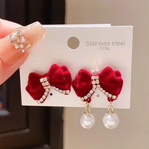 Dettaglio di eleganti orecchini a fiocco in velluto rosso con strass e perle bianche