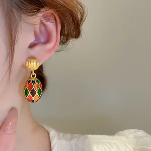 Close-up of vintage French style colorful enamel oval drop earrings on ear