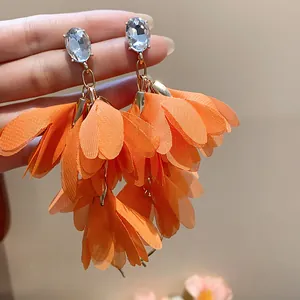 Dettaglio di eleganti orecchini a fiore in chiffon arancione vibrante con cristalli