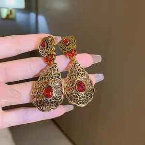Close-up detail of vintage French court style gold filigree earrings with pear-shaped red gems