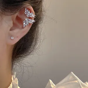 Macro dettaglio di ear cuff in zirconia a forma di foglia sulla pelle