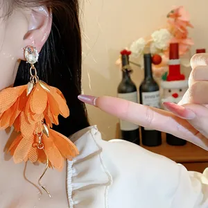 Dettaglio di orecchini a fiore in chiffon arancione con perno in cristallo