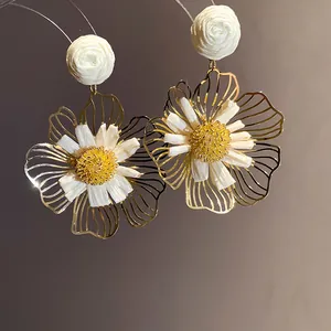 Close-up of elegant gold-toned filigree flower earrings with white raffia centers