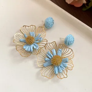 Close-up detail of sweet raffia flower drop earrings with golden hollow wire petals