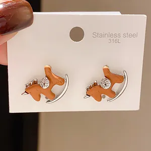 Detailed close-up of brown rocking horse stud earrings with rhinestones on a white display card