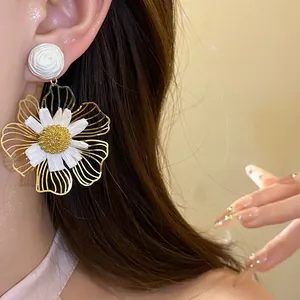 Macro view of elegant white raffia flower drop earrings on model's ear