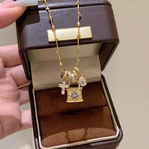 Primo piano dei ciondoli a lucchetto e croce con zirconi su una collana dorata.