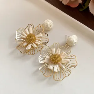 Detailed view of sweet raffia flower dangle earrings with gold hollow petals.