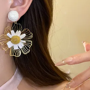 Close-up detail of oversized raffia flower pendant earrings on model with gold accents