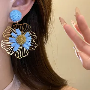 Close-up of elegant blue raffia flower pendant earrings on female model
