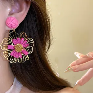 Close-up of pink raffia flower drop earrings on model for detailed texture view
