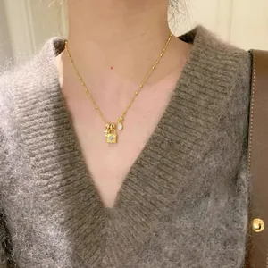 Elegante primo piano di una collana dorata con lucchetto e croce su una modella asiatica
