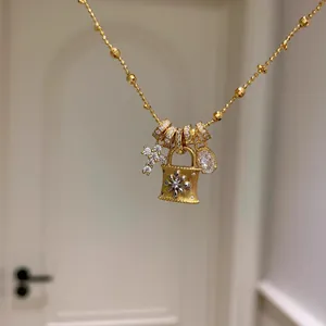 Vista dettagliata di una collana in oro con ciondoli a lucchetto e croce con zirconi.