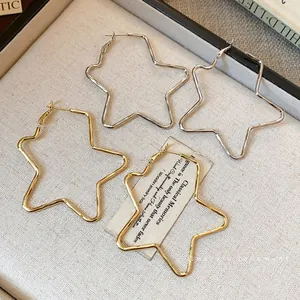 Elegantes pendientes de aro con forma de estrella en oro y plata sobre joyero vintage