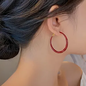 Eleganti grandi orecchini a cerchio in smalto rosso per donna con design minimalista su modella