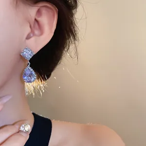 Détail de boucles d'oreilles en zircon brillant en forme de losange pour banquets