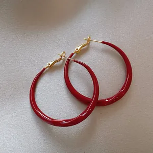 Grandi orecchini a cerchio in smalto rosso con perni in argento e finitura dorata.