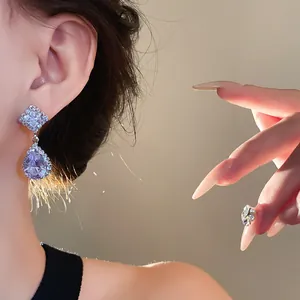 Gros plan sur d'élégantes boucles d'oreilles en zircon portées par un mannequin.