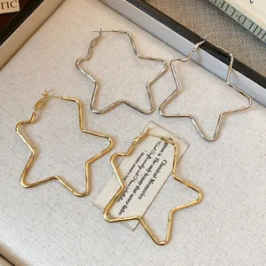 Primer plano de pendientes de aro minimalistas con forma de estrella en oro y plata