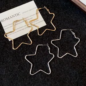 Primer plano de pendientes de aro minimalistas con forma de estrella dorados y plateados en tela