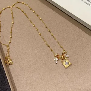 Primo piano della collana placcata in oro con ciondoli a lucchetto e croce con zirconi