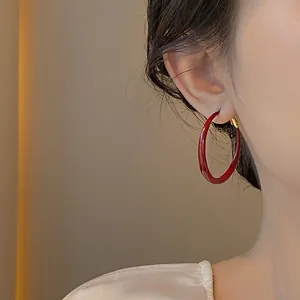 Vista dettagliata di un grande orecchino a cerchio smaltato rosso indossato da una modella