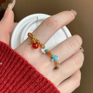 Primo piano di anello elastico con perline dorate, fiore e ciondolo in pietra rossa