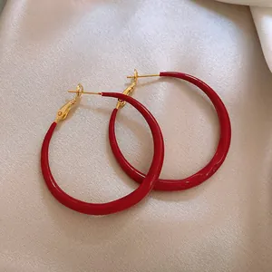 Dettaglio di grandi orecchini a cerchio in smalto rosso con chiusura ad ago in argento