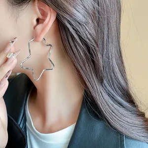 Primer plano de un pendiente de aro con forma de estrella plateada en una modelo