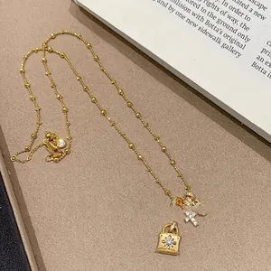 Primo piano squisito di ciondoli a lucchetto e croce dorati con zirconi brillanti