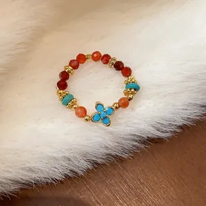 Vista dettagliata di un anello elastico con perline colorate e ciondolo a forma di fiore dorato