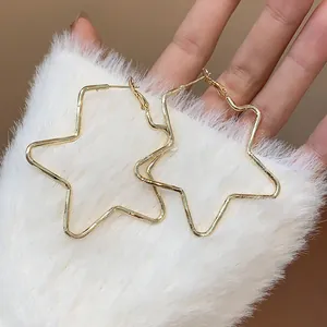 Detalle de pendientes de aro con forma de estrella dorada sobre fondo de pelo blanco.