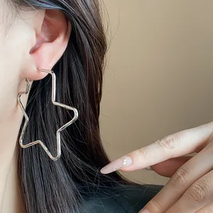 Primer plano de un pendiente de aro de plata minimalista con forma de estrella en una modelo