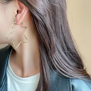 Primer plano detallado de elegantes pendientes de aro dorados con forma de estrella