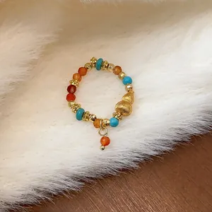 Dettaglio macro di un anello elastico con perline occhio di tigre e ciondolo oro