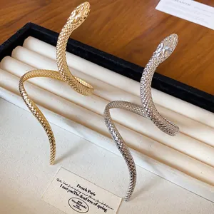 Detailed view of gold and silver twisted snake-shaped bracelets with scale texture