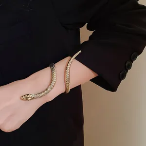 Luxurious golden snake-shaped wrap bracelet featuring intricate scale texture worn over a black blazer