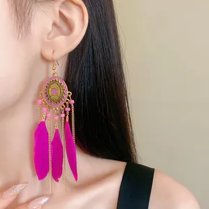 Nahaufnahme der böhmischen Retro-Ohrringe mit rosa Federn und goldenen Tropfenmotiven