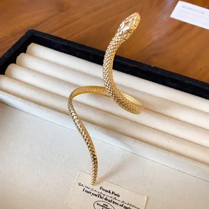 Detailed close-up of a gold-colored twisted snake bracelet with textured scales