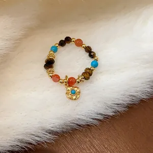 Primo piano dettagliato dell'anello elastico con perline occhio di tigre e fiore d'oro