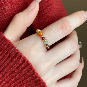 Dettaglio di un anello elastico con perline di pietre preziose colorate e finiture in oro.