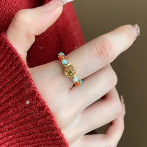 Dettaglio ravvicinato di un anello elastico con perline e testa di tigre placcata oro