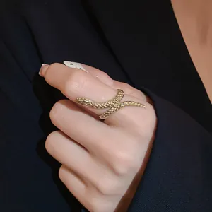 Close-up of a gold-toned wrap-around snake ring with textured scale details on a finger
