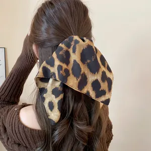 Dettaglio di un elastico per capelli vintage in tessuto leopardato su una coda di cavallo castana