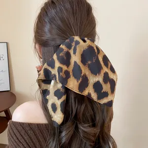 Dettaglio del foulard per capelli in tessuto leopardato vintage legato a una coda.