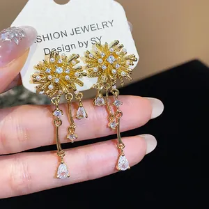 Close-up showing details of 18k gold plated firework earrings with zirconia and pearls.