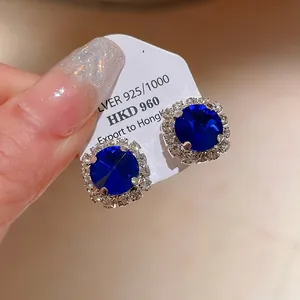 Close-up macro view of elegant blue crystal stud earrings with shimmering clear stones