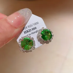 Macro detail showing emerald green stud earrings with silver 925 hallmark on display card